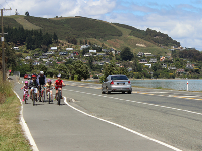 Kids riding their own bike on the road with an adult